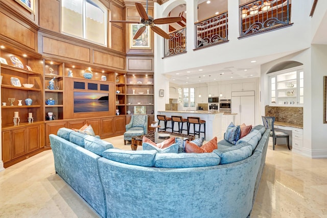 living room with marble finish floor, built in features, a towering ceiling, recessed lighting, and ceiling fan