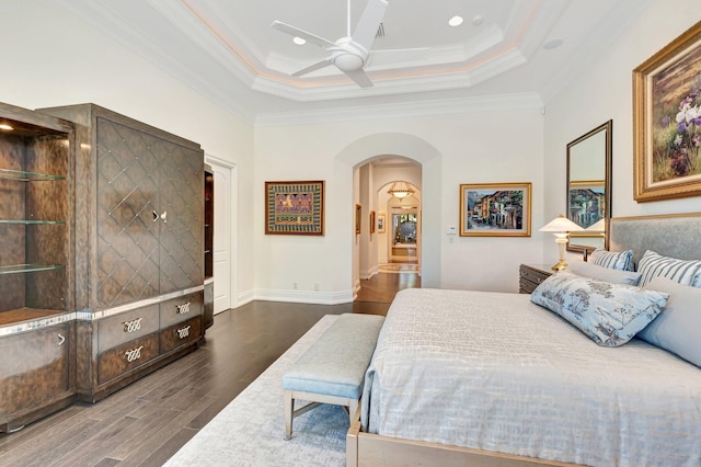 bedroom featuring crown molding, ceiling fan, wood finished floors, arched walkways, and a raised ceiling