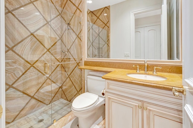 bathroom featuring a shower stall, toilet, and vanity