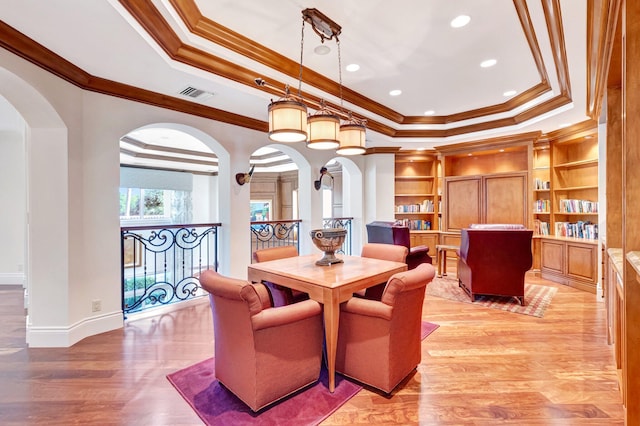 dining room featuring light wood-type flooring, visible vents, a raised ceiling, and arched walkways