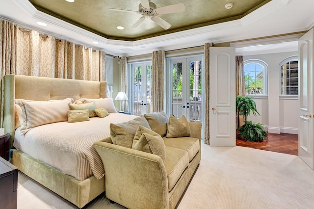 carpeted bedroom featuring baseboards, a tray ceiling, ornamental molding, recessed lighting, and french doors
