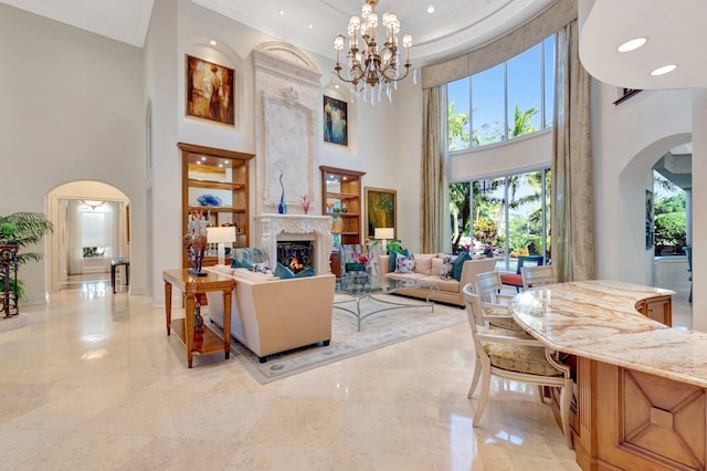 living area featuring a chandelier, ornamental molding, a fireplace, a high ceiling, and arched walkways