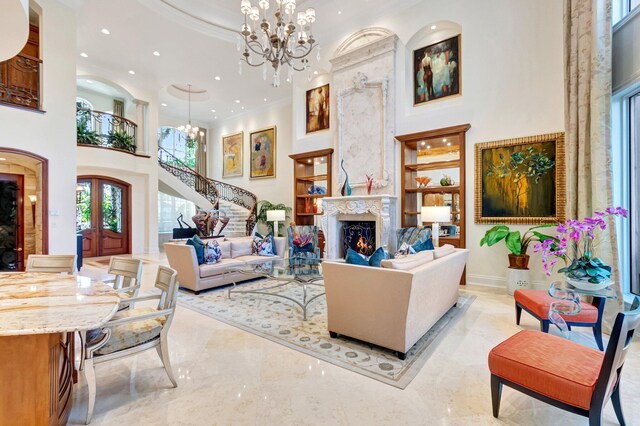 living room featuring ornamental molding, french doors, a high ceiling, a fireplace, and a chandelier