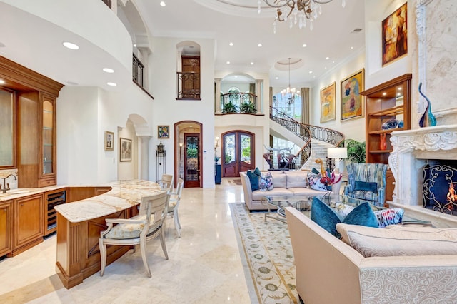 living area with recessed lighting, wine cooler, arched walkways, crown molding, and a chandelier