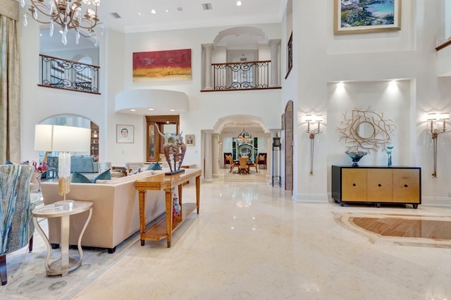 entryway with arched walkways, a notable chandelier, marble finish floor, and a towering ceiling
