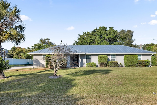 ranch-style home featuring fence, metal roof, and a front yard