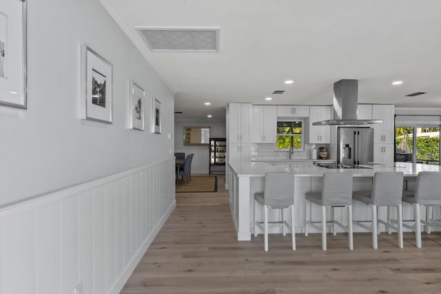 kitchen with white cabinetry, range hood, high quality fridge, and visible vents