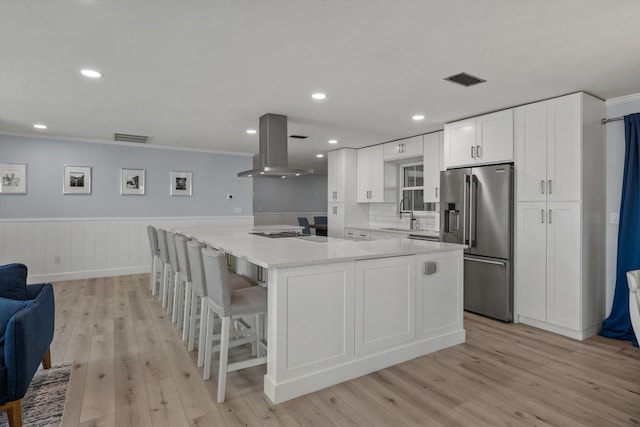 kitchen featuring island exhaust hood, visible vents, light wood-style flooring, white cabinetry, and high quality fridge