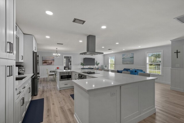 kitchen featuring black electric stovetop, light wood-style flooring, a wainscoted wall, freestanding refrigerator, and island exhaust hood