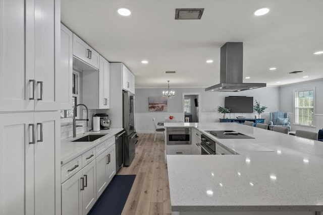 kitchen featuring a spacious island, visible vents, a sink, island range hood, and black appliances