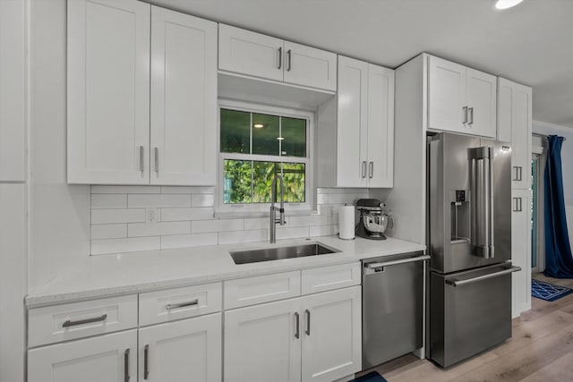 kitchen with stainless steel appliances, white cabinetry, a sink, and decorative backsplash