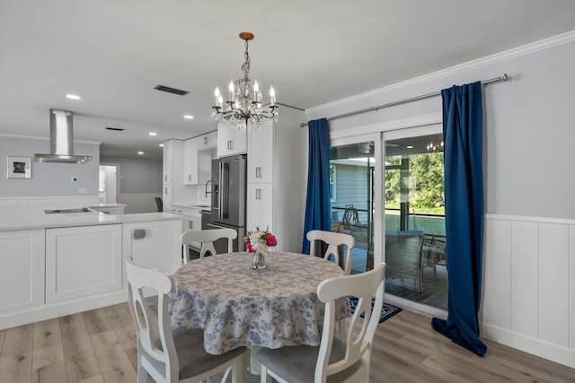 dining space featuring light wood-style floors, wainscoting, visible vents, and crown molding