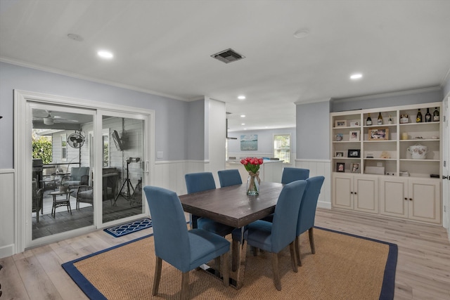 dining room with a wainscoted wall, light wood-style flooring, a wealth of natural light, and visible vents