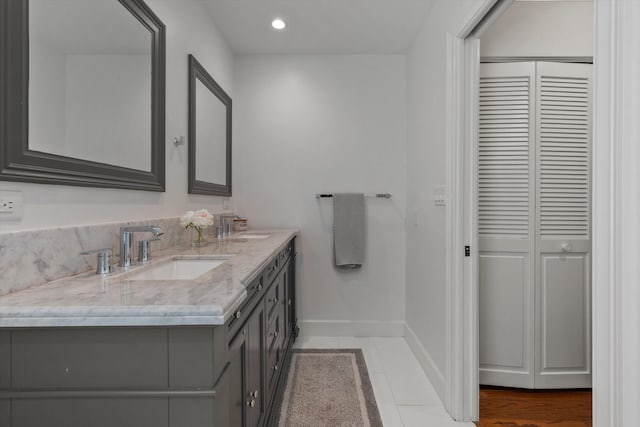 bathroom featuring tile patterned floors, a sink, baseboards, and double vanity