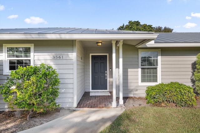 entrance to property featuring metal roof, a standing seam roof, and solar panels