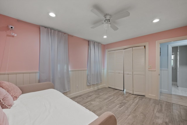 bedroom with light wood-type flooring, a closet, wainscoting, and recessed lighting