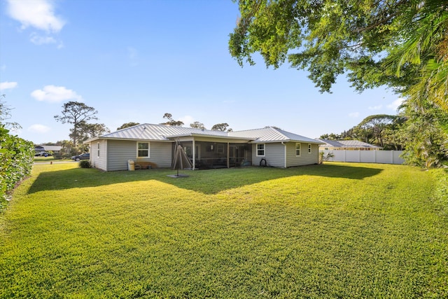 back of house with metal roof, a yard, a fenced backyard, and a sunroom