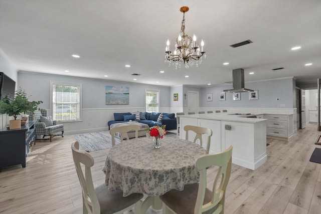 dining space featuring light wood-style flooring, wainscoting, visible vents, and crown molding