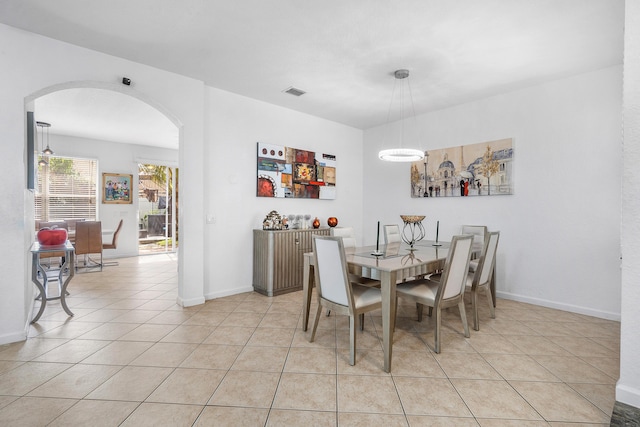 dining area with arched walkways, light tile patterned floors, visible vents, and baseboards