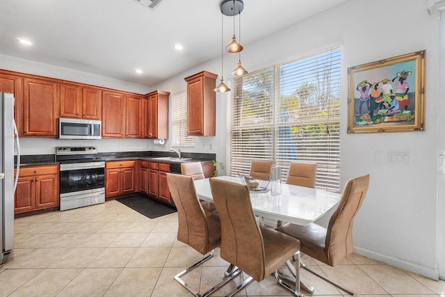 kitchen with pendant lighting, light tile patterned floors, stainless steel appliances, dark countertops, and a sink