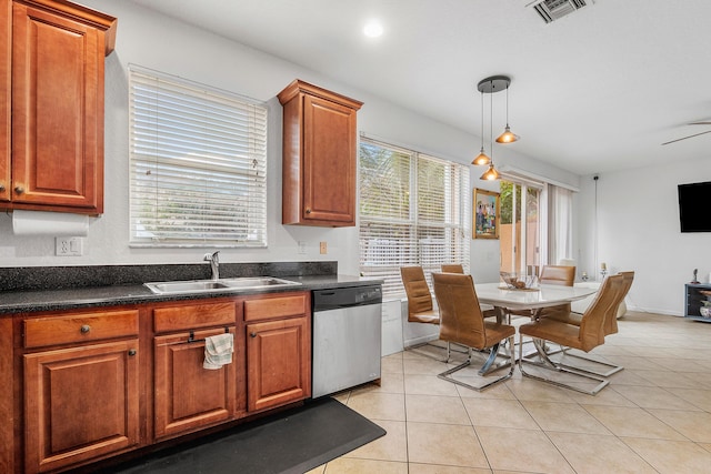 kitchen with light tile patterned floors, visible vents, dark countertops, stainless steel dishwasher, and a sink