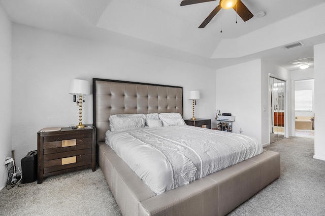 bedroom featuring a tray ceiling, carpet, ensuite bath, and visible vents