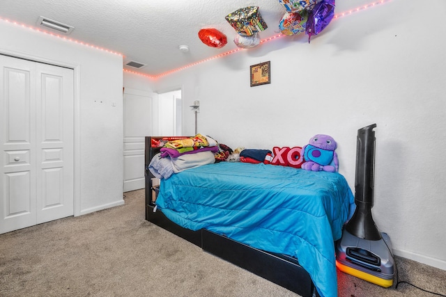 bedroom featuring carpet, a closet, visible vents, and a textured ceiling