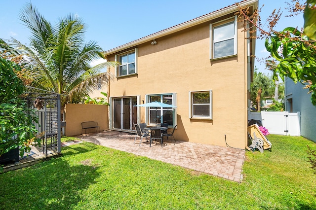 back of house featuring a gate, a fenced backyard, a lawn, and stucco siding