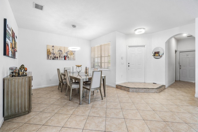 dining space featuring arched walkways, visible vents, baseboards, and light tile patterned floors