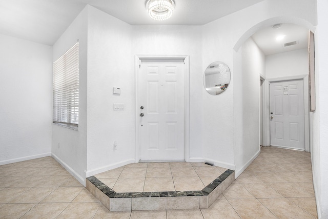 foyer with tile patterned flooring, visible vents, arched walkways, and baseboards