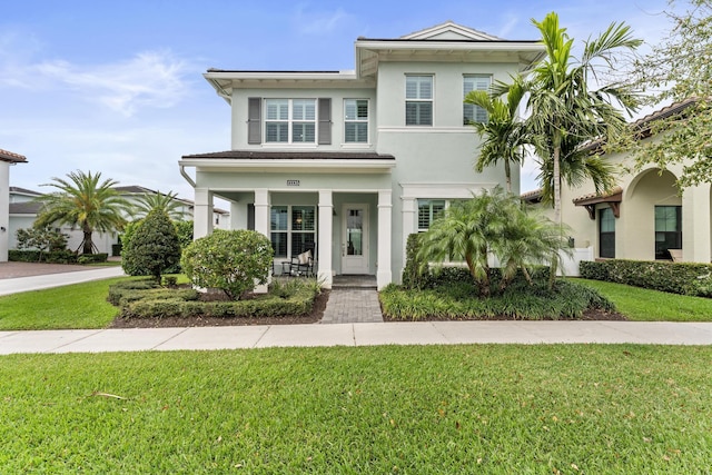 view of front of house featuring covered porch, a front yard, and stucco siding