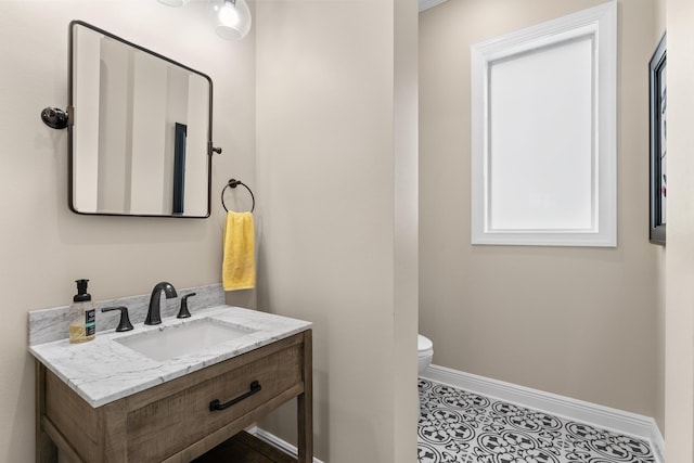 bathroom featuring toilet, tile patterned floors, baseboards, and vanity