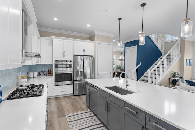 kitchen featuring stainless steel appliances, a sink, light countertops, gray cabinets, and crown molding