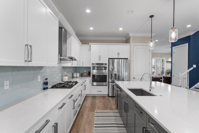 kitchen with decorative backsplash, stainless steel appliances, crown molding, wall chimney range hood, and a sink