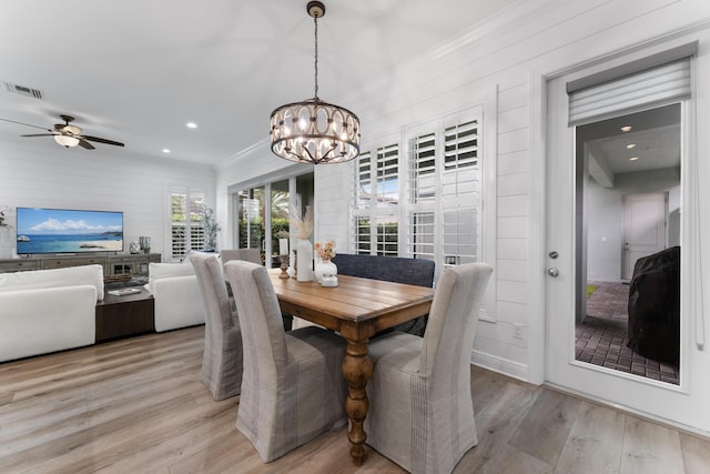 dining space with light wood-style flooring, recessed lighting, ceiling fan with notable chandelier, visible vents, and crown molding