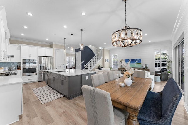 dining room with recessed lighting, stairway, ornamental molding, a chandelier, and light wood-type flooring