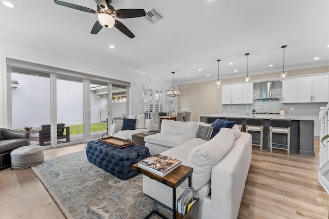 living room with ornamental molding, visible vents, and light wood-style floors