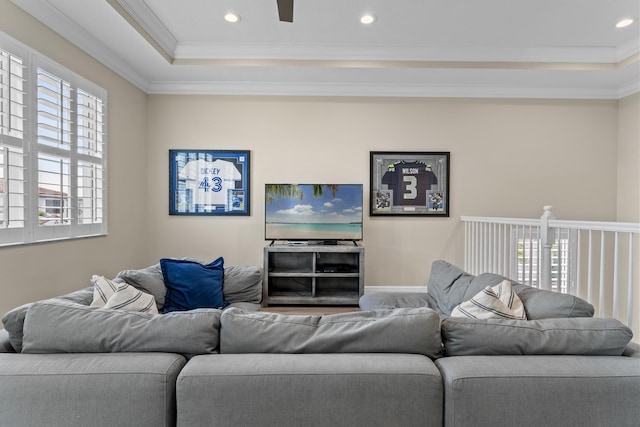 living area with baseboards, a raised ceiling, crown molding, and recessed lighting