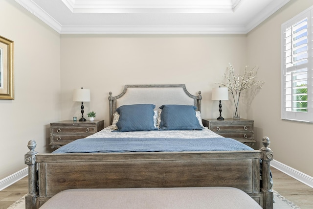 bedroom with baseboards, a tray ceiling, wood finished floors, and crown molding