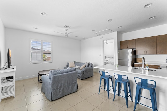 living area with light tile patterned flooring, recessed lighting, visible vents, baseboards, and attic access