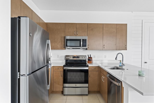 kitchen with light tile patterned floors, stainless steel appliances, a sink, and light countertops