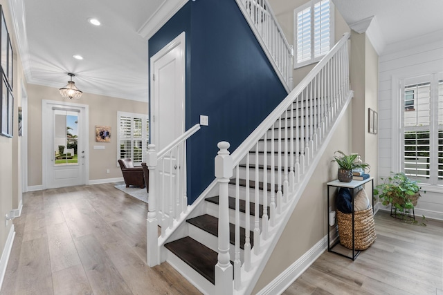 stairs with a healthy amount of sunlight, baseboards, ornamental molding, and wood finished floors