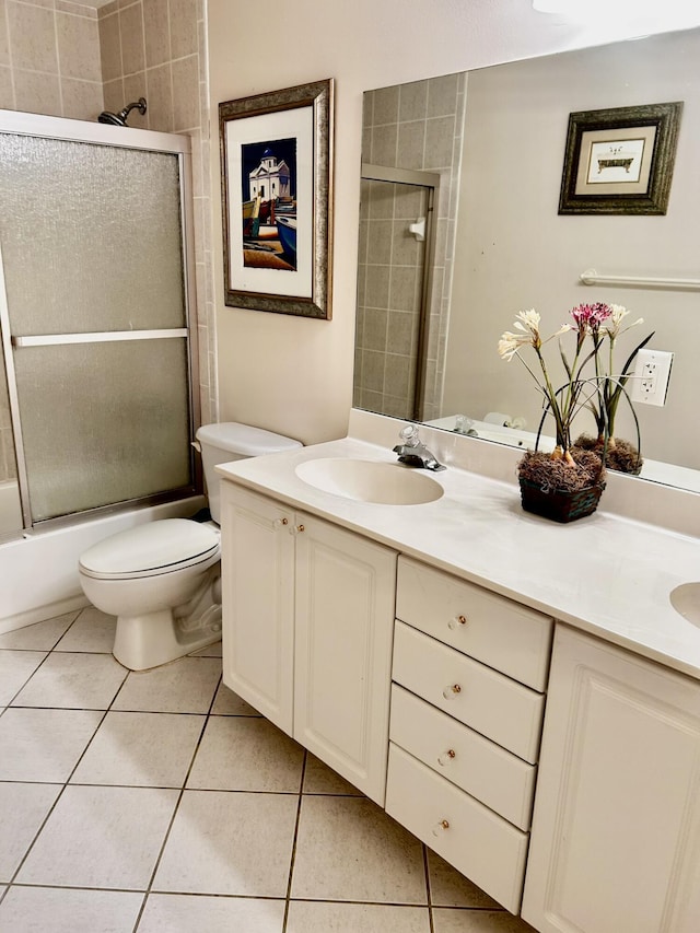 full bath featuring bath / shower combo with glass door, double vanity, toilet, a sink, and tile patterned floors