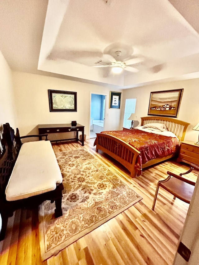 bedroom featuring a tray ceiling, ceiling fan, and wood finished floors