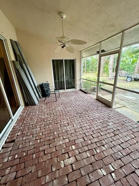 unfurnished sunroom featuring a ceiling fan