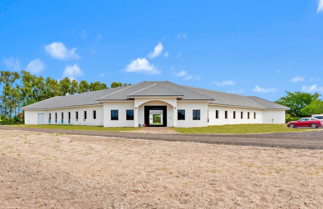 view of front of house featuring a front lawn, a tile roof, and stucco siding