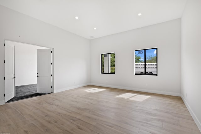 empty room with light wood-style floors, baseboards, and recessed lighting