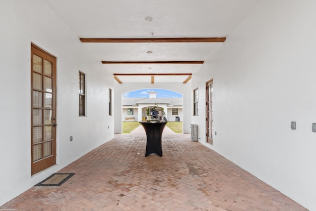 interior space featuring brick floor, french doors, visible vents, and beamed ceiling