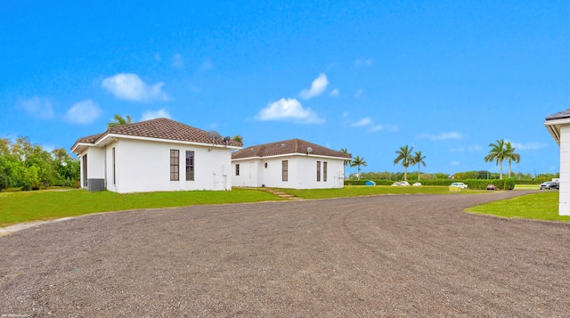 12940 50th St S, Wellington, FL 33449 - view of front facade with a tiled roof, central AC unit, a front lawn, and stucco siding