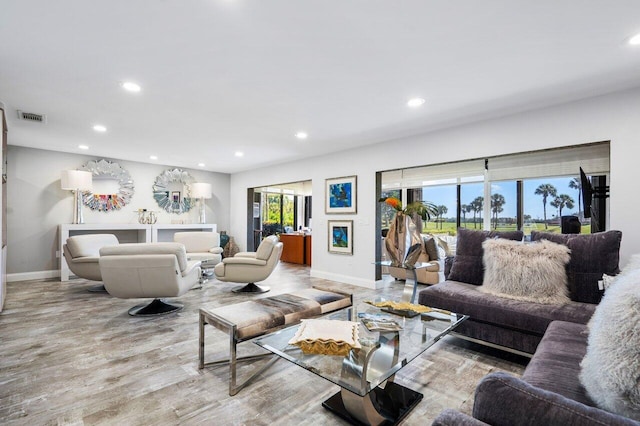 living room featuring baseboards, visible vents, wood finished floors, and recessed lighting